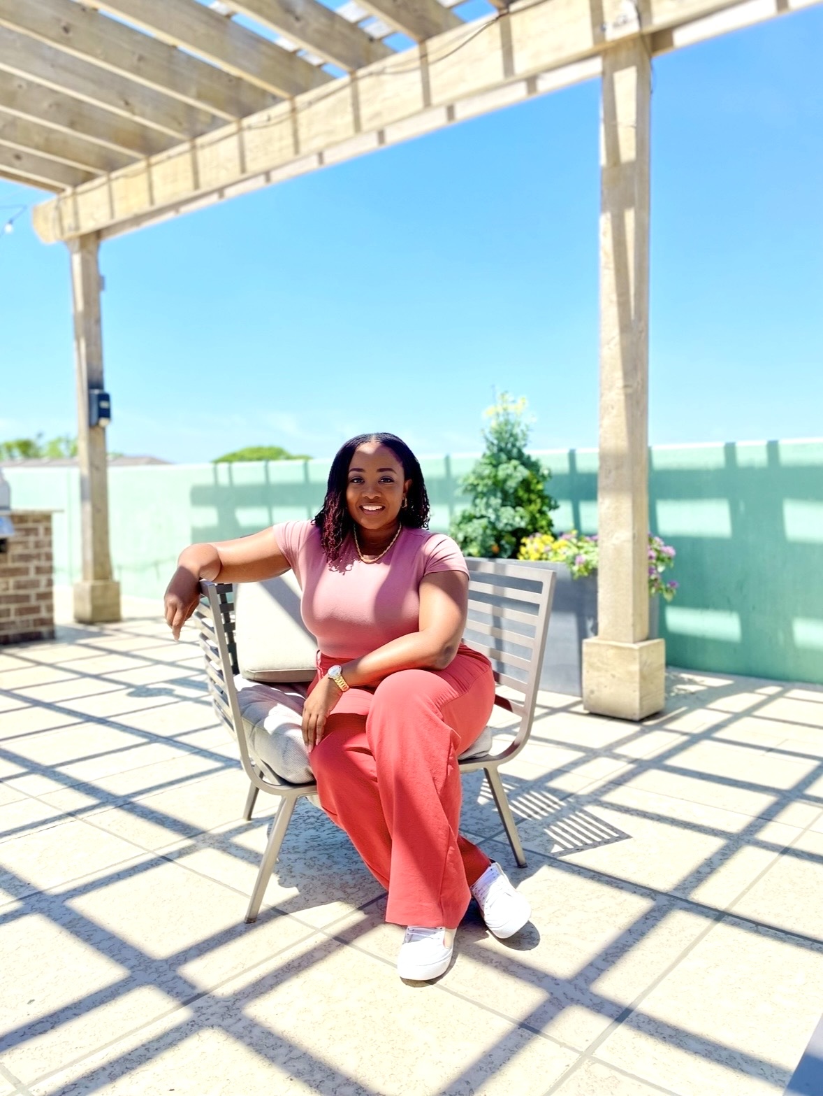Ashley Catan, UX Strategist, seated on a sunlit rooftop patio.